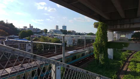tren pasando bajo un puente con edificios en la ladera de la colina en el fondo en tokio, japón