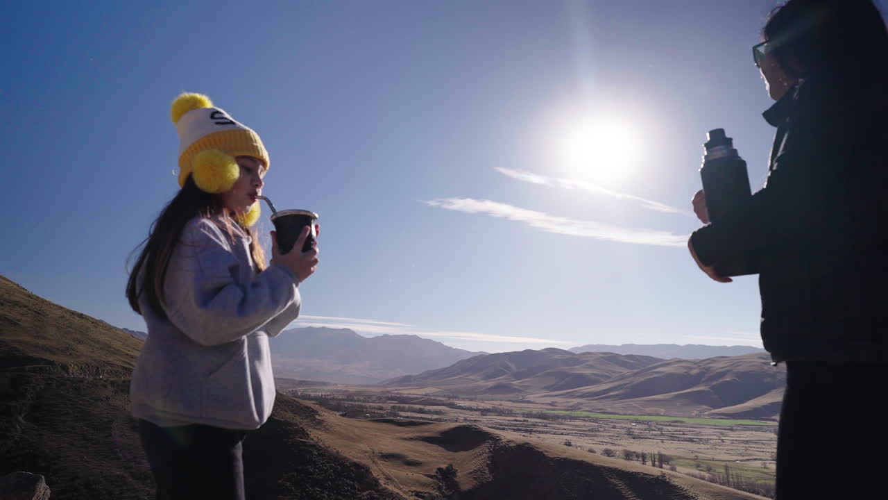 Mother sharing traditional South American yerba mate drink with daughter, cultural heritage