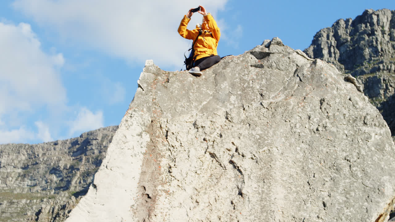 고령 여성이 바위 4k에 휴대전화로 사진을 클릭하고 있습니다.