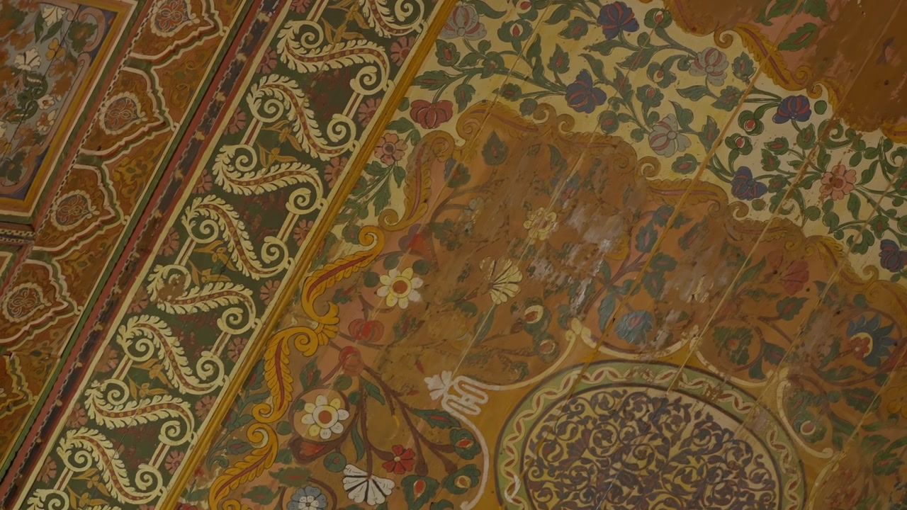 Techo pintado ornamentado con motivos florales y geométricos en un interior de Marrakech.