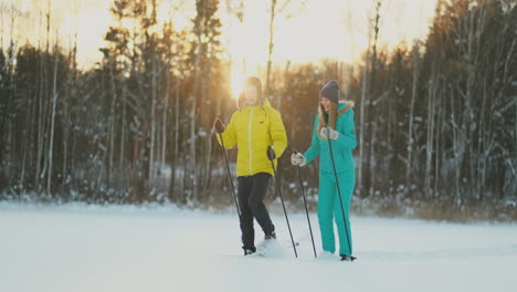 side view portrait of active young couple carrying skis chatting on the way back in beautiful winter forest, copy space