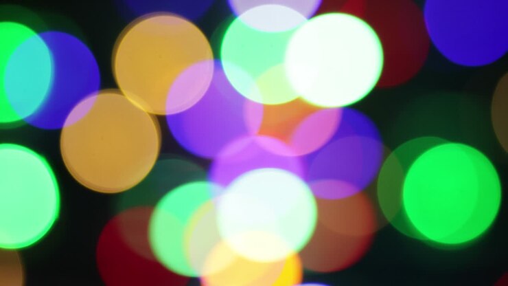 Christmas blur background. Shimmering colored circles defocused christmas lights video. Multicolored light leaks 4k footage on black background. Happy New Year