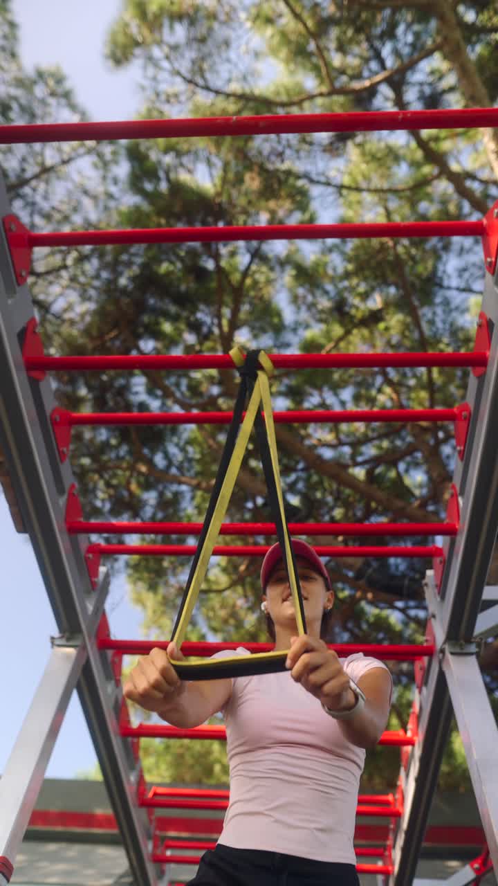Woman using resistance band on outdoor exercise equipment