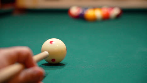 slow motion billiards low angle close up as person breaks a rack of 8 ball baddly flying the cue ball off the pool table with green felt and the cue stick bending as both solid and stipe balls skatter