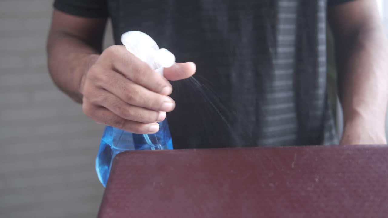 스프레이 병 으로 표면 을 청소 하는 사람