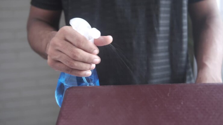 Person cleaning a surface with a spray bottle