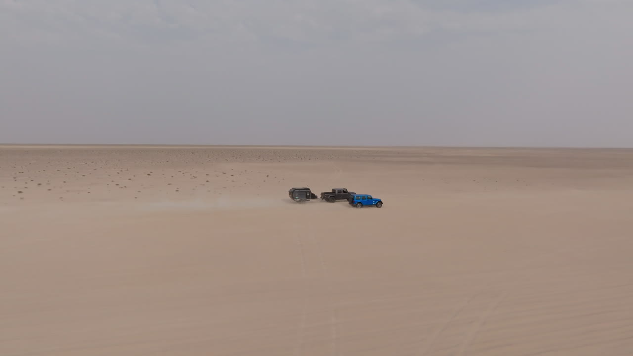 Trucks driving fast through Oman desert on road to Bar Al Hikman, wide open and dry