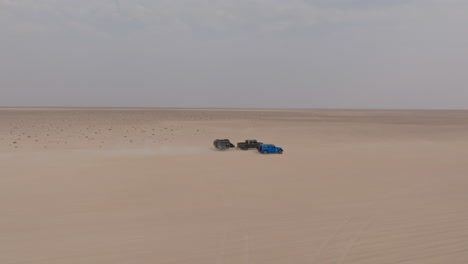 trucks driving fast through oman desert on road to bar al hikman, wide open and dry