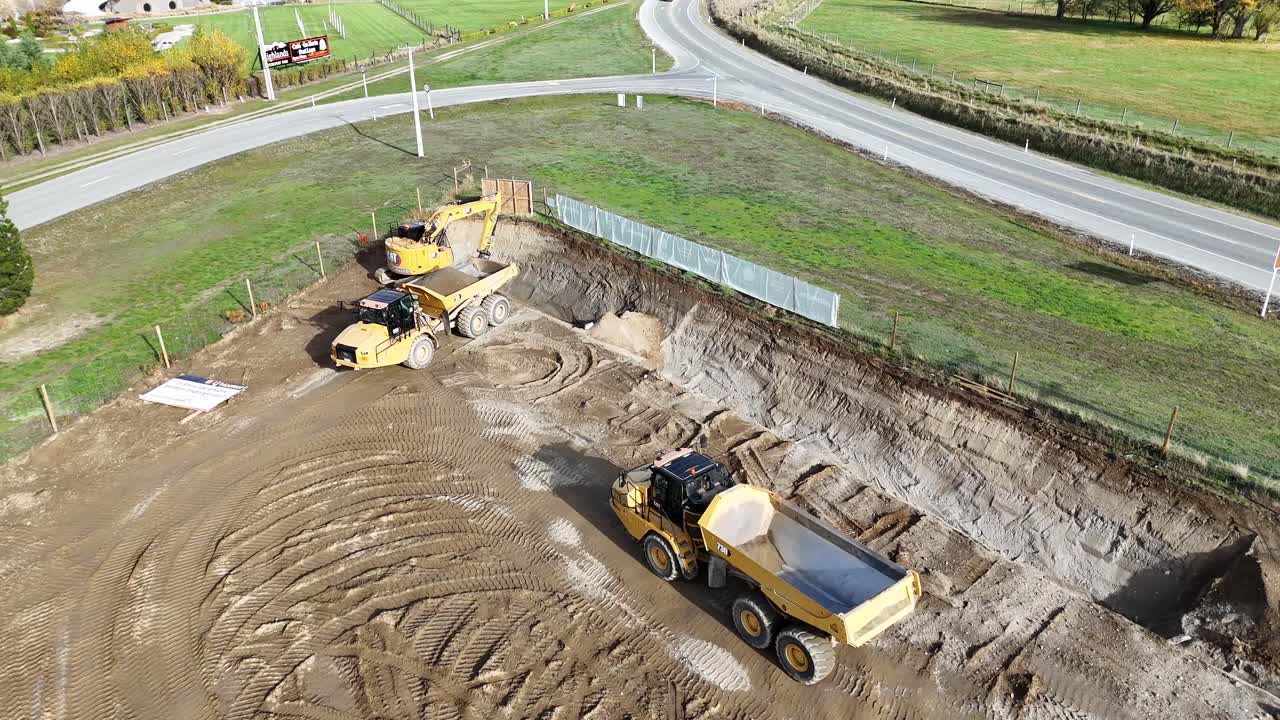 Drone footage captures excavator and dump truck at work on a sunny day in Cromwell, New Zealand