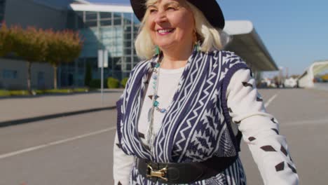 Portrait-of-senior-pensioner-tourist-grandmother-stay-near-airport-hall-waiting-for-plane,-travel