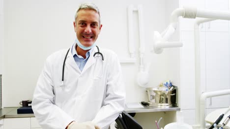 Smiling-dentist-standing-in-dental-clinic