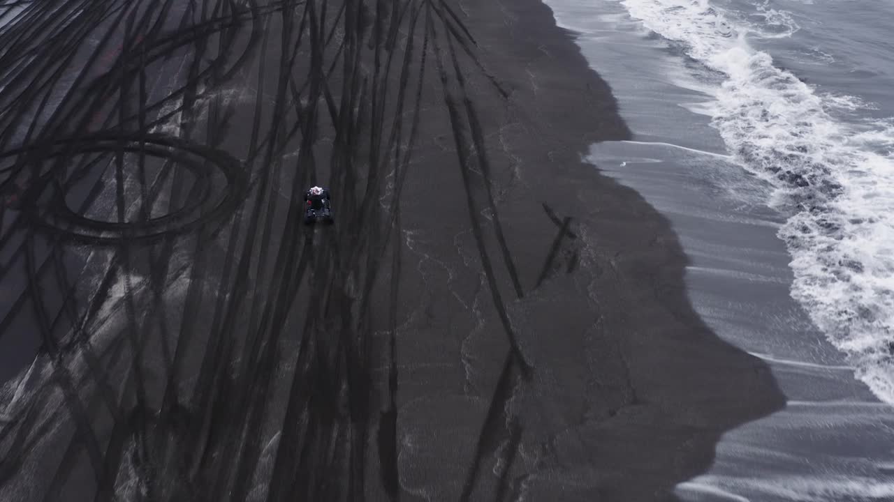 Uomo in quad che accelera e impenna su una spiaggia nera in Islanda.