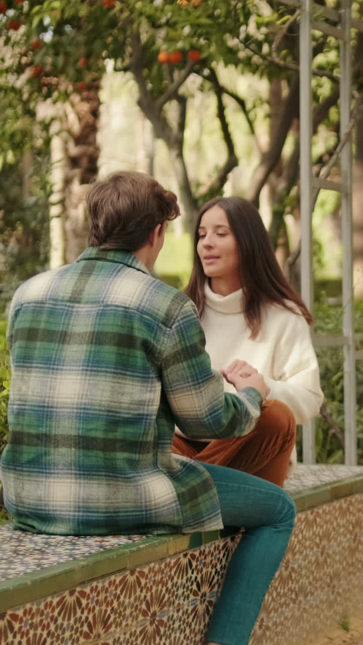 Jóvenes socios, un hombre y una mujer, charlando sentados en un parque