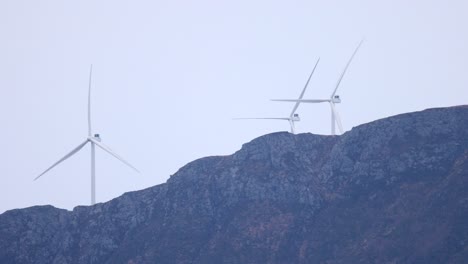 Wind-turbines-sticking-up-behind-a-mountain-peak