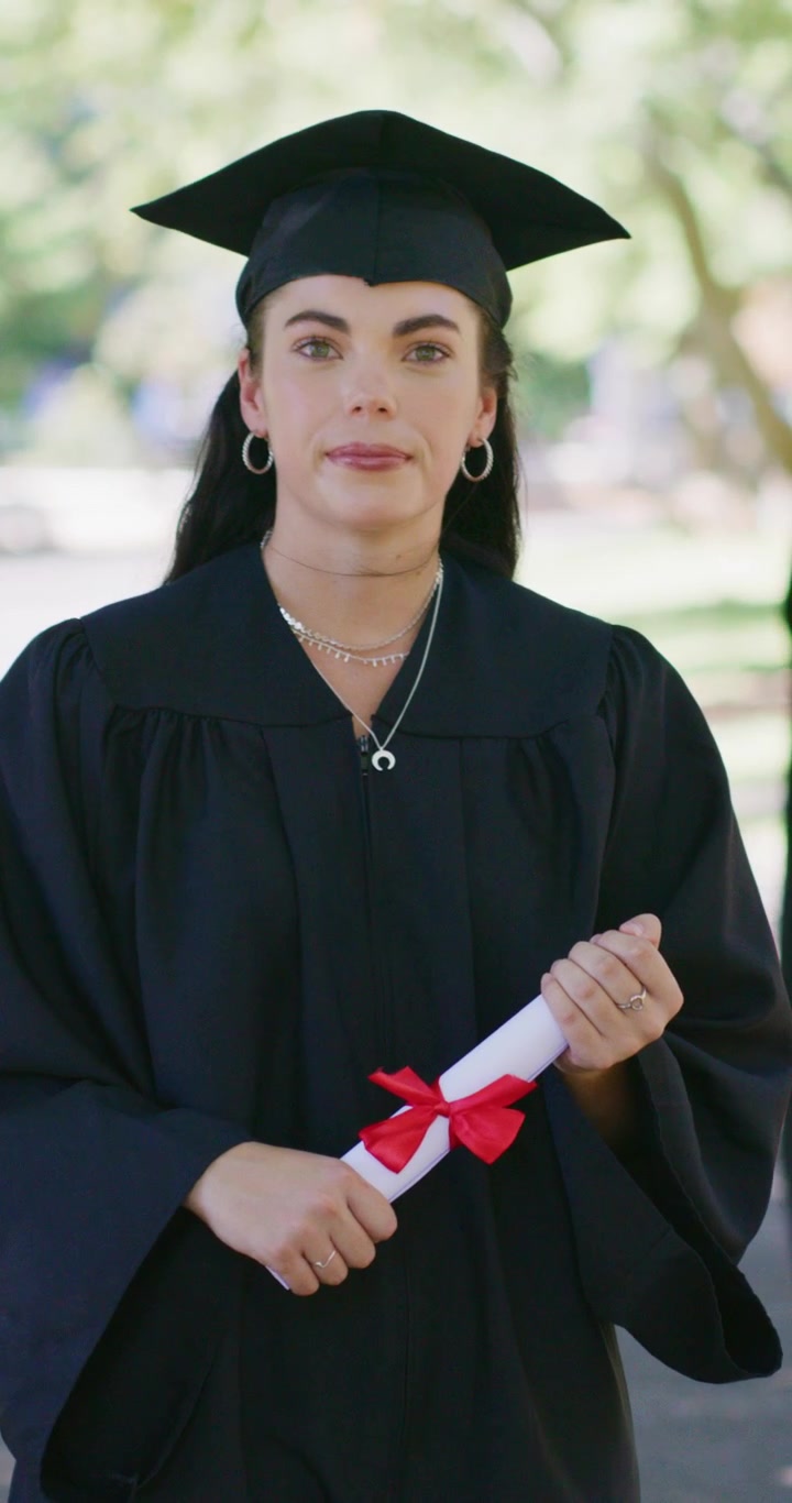 Giovane donna in abito da laurea con il diploma in mano