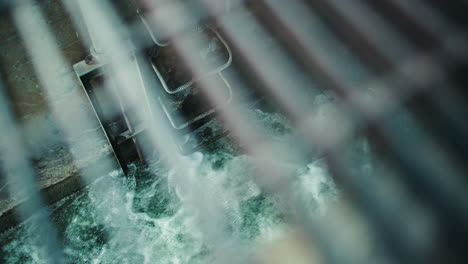 rushing flood water in sewer drainage overflow tunnel through metal grate