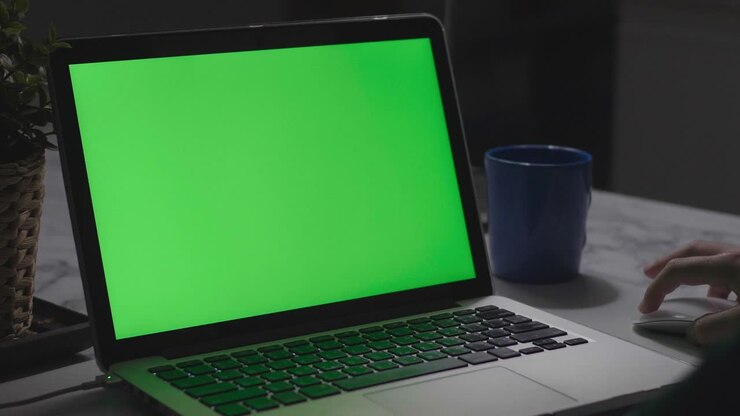 Über-die-Schulter-Aufnahme eines jungen Jungen, der einen Laptop-Computer auf dem Schreibtisch benutzt und auf einen grünen Bildschirm blickt. Dolly-Aufnahme 60fps.