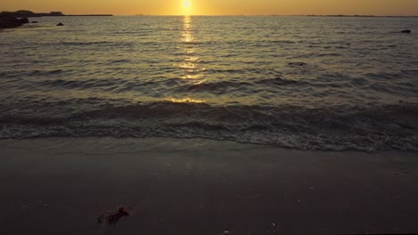 a coastal view of the midnight sun over calm ocean. white sand beach and island in background. lofoten islands, northern norway. slow motion 120 fps.