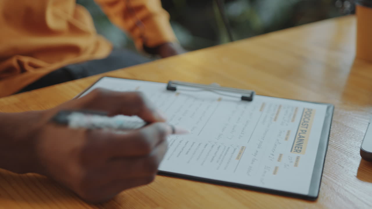 Hands of Podcast Presenter Proofreading Content Planner and Taking Notes