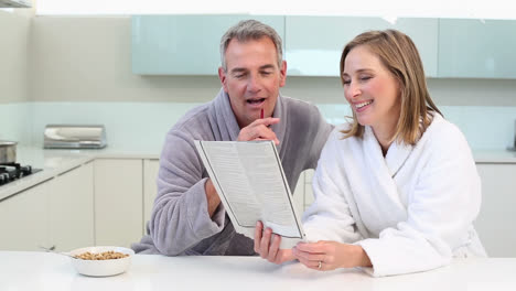 una pareja madura y sonriente haciendo el crucigrama en el desayuno.