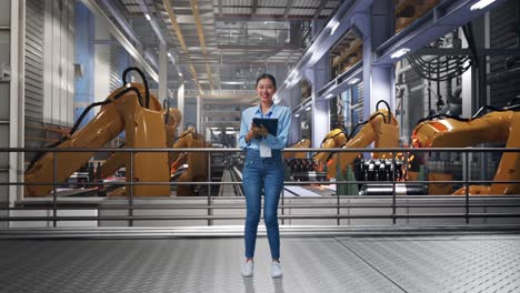 full body of asian female with industrial robotic arms working, typing on tablet's keyboard and looking camera and smiling