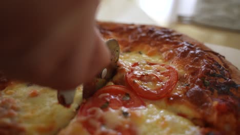 cutting hot steamy margarita pizza into slices, dolly in, following hand