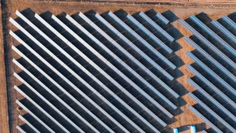 drone flying around solar power plant. autumn yellow field with rows of solar panels at sunset