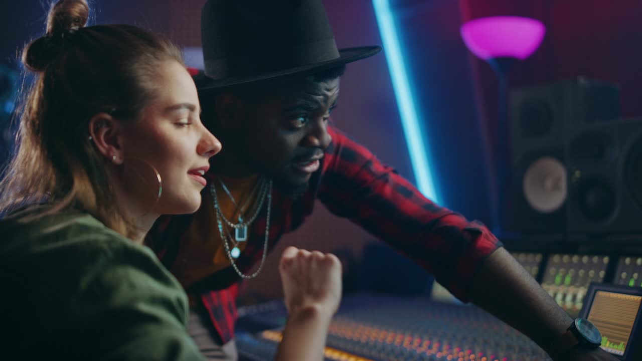 Producent och ljudtekniker arbetar tillsammans i en musikstudio med ett nytt album, pratar, använder kontrollbordets equalizer, mixerbord och mjukvara för att skapa en hitlåt. Artist- och musikersamarbete. Handhållen.