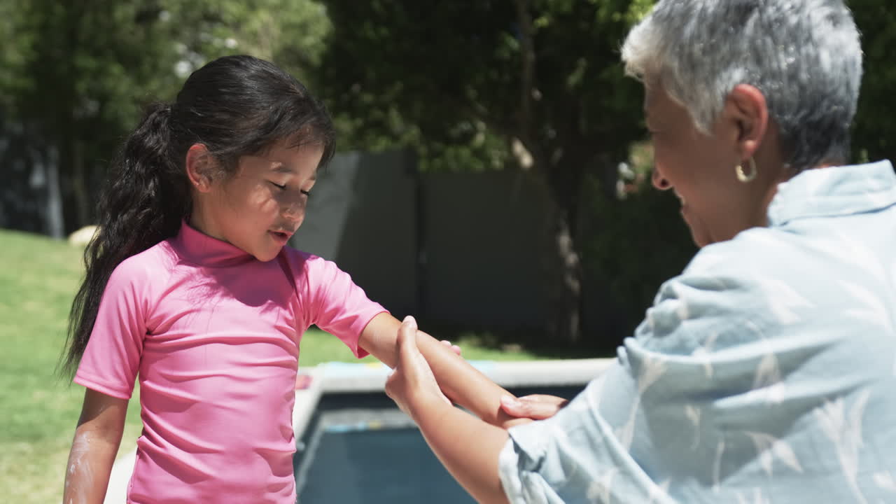 una chica biracial con cabello largo y negro en una camiseta rosa recibe algo de su abuela