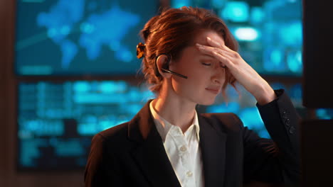 Statische-Aufnahme,-Eine-Geschäftsfrau-Bei-Der-Arbeit,-Die-über-Ihr-Bluetooth-Headset-Spricht,-In-Einer-Kundendienstbranche,-Mit-Starker-Migräne-Und-Kopfschmerzen