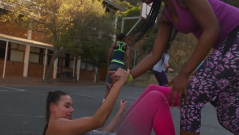 diverse female basketball team playing match, helping each other