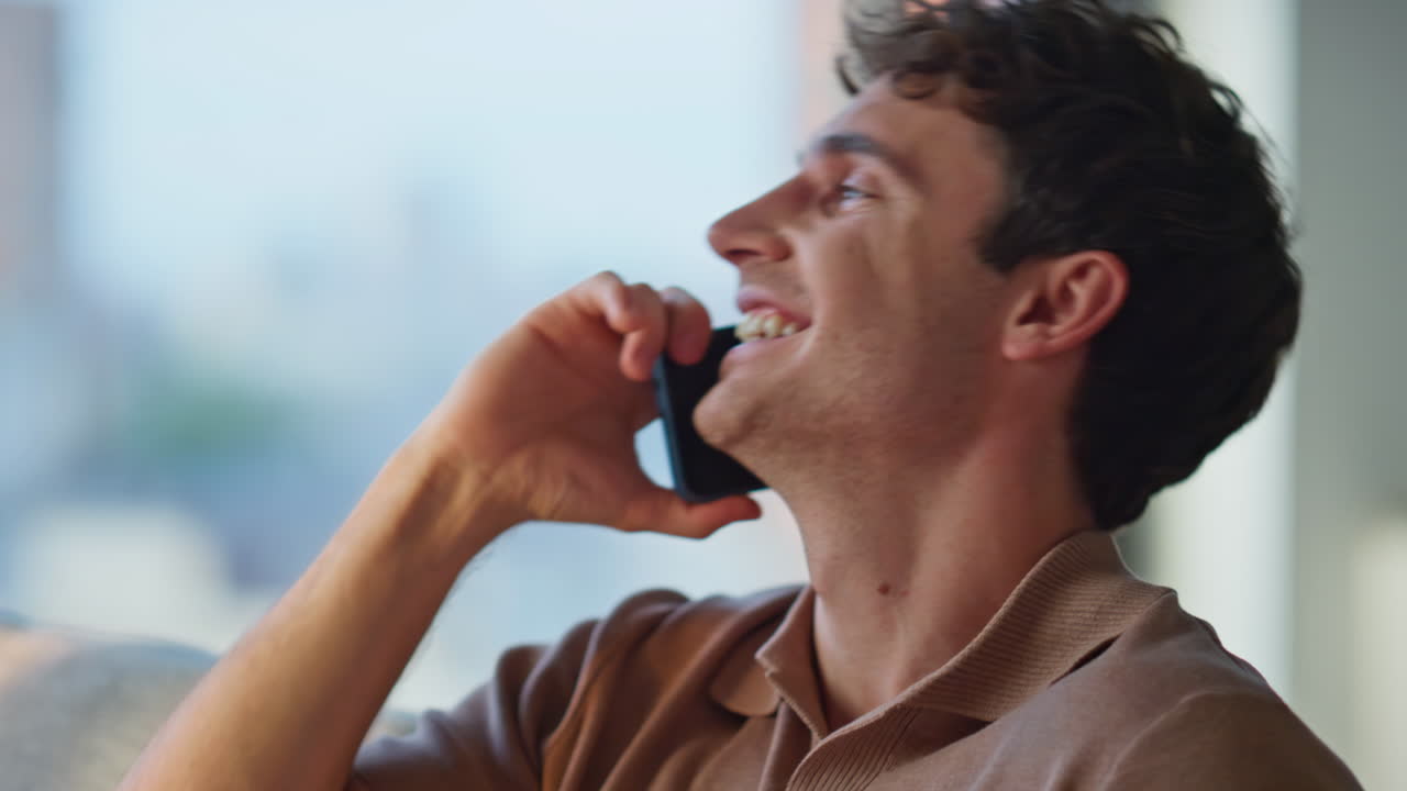 Happy man laughing smartphone sitting on sofa cozy home closeup. Smiling guy