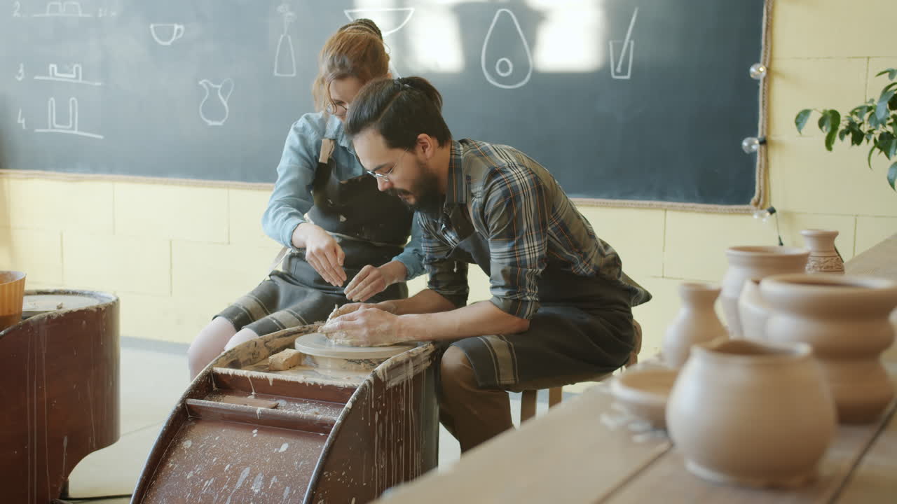 Two people learning pottery in a workshop