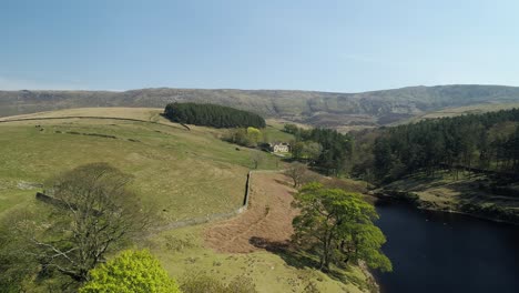 Toma-Aérea-Panorámica-Sobre-El-Agua-Del-Embalse-De-Kinder-Que-Muestra-Una-Finca-De-Fideicomiso-Nacional-En-La-Distancia-Ubicada-En-El-Valle-De-Kinder-Scout