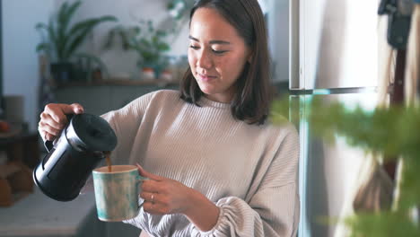 a woman pouring herself coffee from a plunger