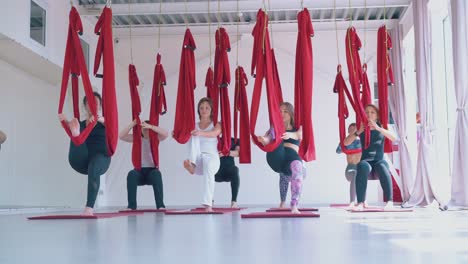 women group practices anti-gravity yoga and stretches legs