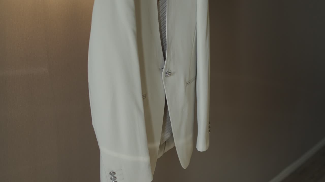 Close-up of a white suit jacket hanging, showcasing its sleek and modern design