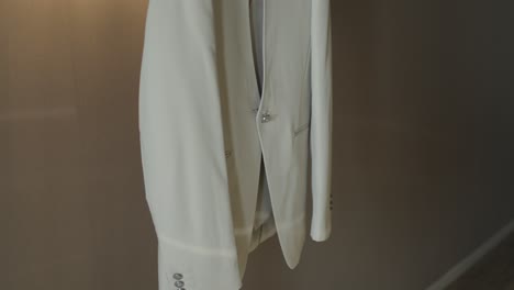 close-up of a white suit jacket hanging, showcasing its sleek and modern design