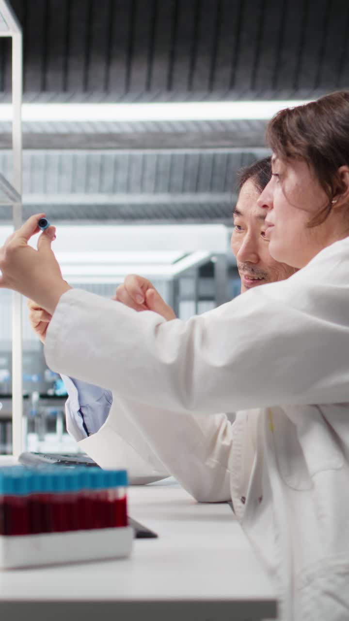 Vertical video Senior laboratory expert and trainee analyzing batch of blood samples