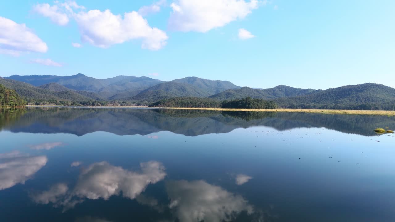 晴れた日に、山と空を映し出す穏やかな湖