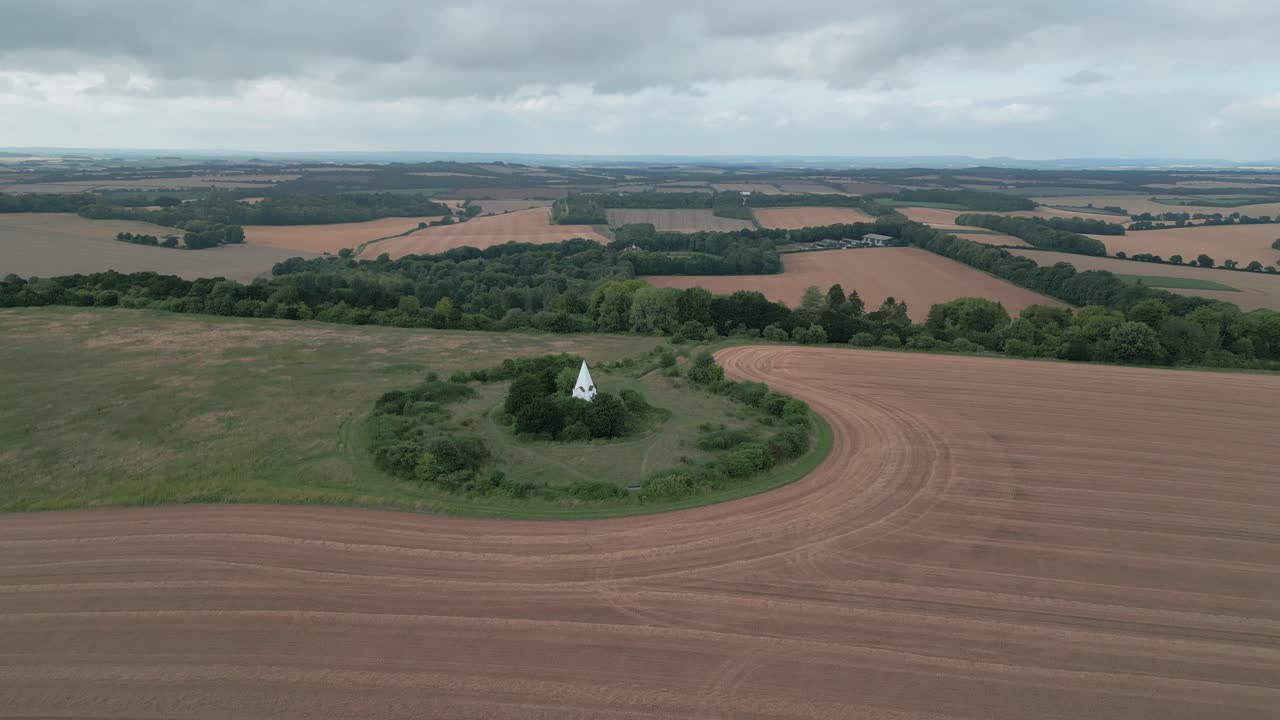 Aerial orbit of Farley Mount Monument, Winchester, UK, surrounded by open fields and natural landscape