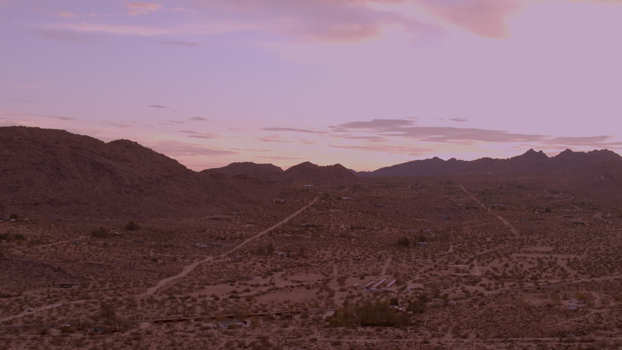 Un cielo magnifico all'alba a Joshua Tree con una strada sterrata solitaria che si estende verso le colline frastagliate