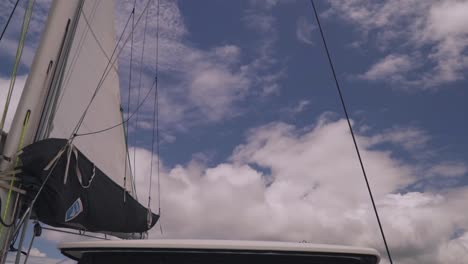 a catamaran sailing away from pacific island in the distance with blue skies