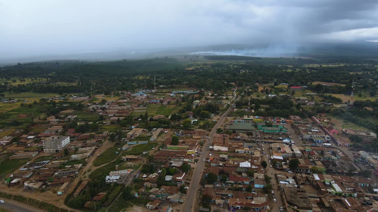 vista aérea sobre el pueblo de loitokitok en el área de amboseli de kenia, fondo de incendios forestales tropicales - aumento, disparo de drones