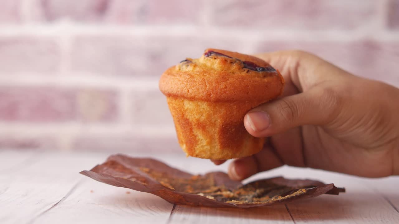 Mano che tiene un muffin ai mirtilli