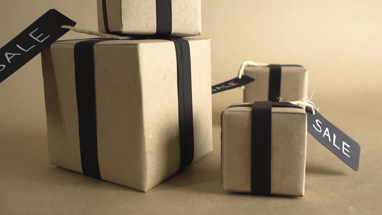 Stylish gift boxes wrapped in brown craft paper with black ribbons and sale tags, ideal for promoting special offers, discounts, and holiday shopping events like Black Friday or Cyber Monday