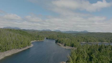 Drone-flying-forward-showing-islands-and-surrounding-ocean-and-trees-on-a-beautiful-sunny-day-with-clouds-in-the-background