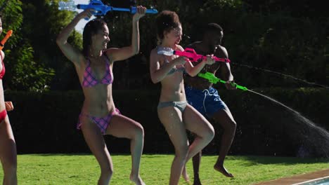 mixed race woman having fun playing with water guns and jumping into swimming pool