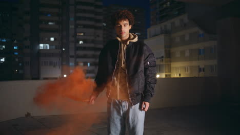 man holding red grenade in dark town late evening. guy burning colorful smoke