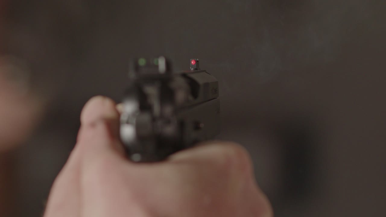Overshoulder of 9mm pistol being fired and a casing being ejected in slow motion